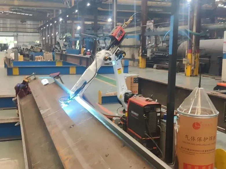Welding robot on a rail welding along the flange of a long H-beam.