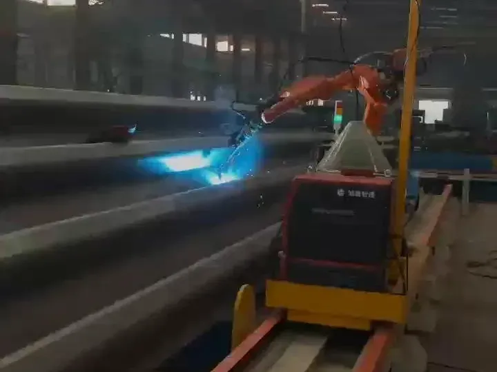 Robot sur rail soudant de longs raidisseurs en acier, avec un arc lumineux.