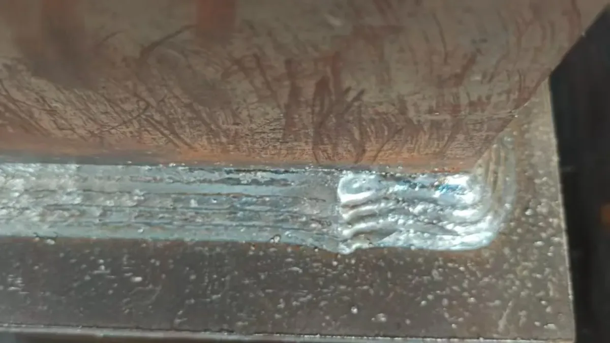 Vista cercana de una soldadura de filete robotizada en una placa de acero.