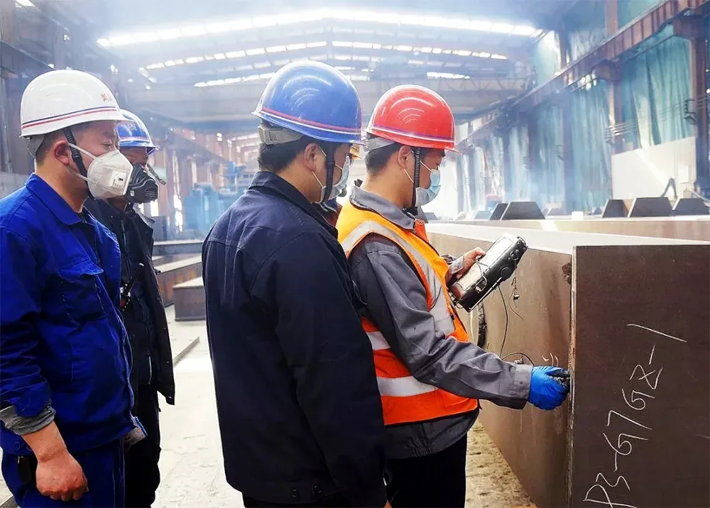Personnel examining a fabricated steel component inside our workshop.
