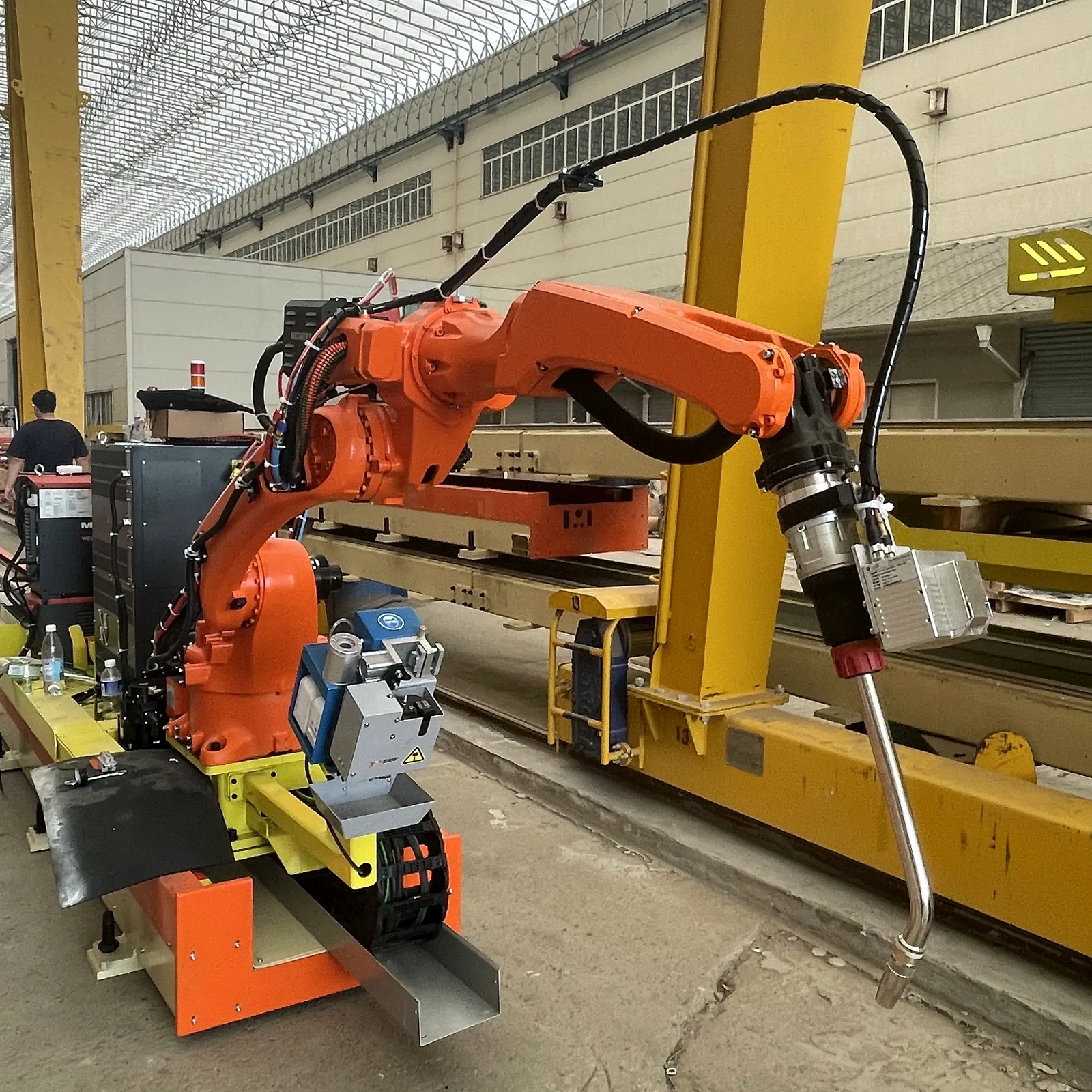 Orange rail-mounted welding robot with torch and camera equipment in a Honglu factory