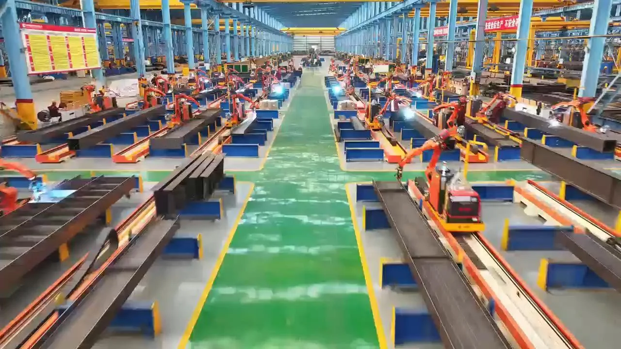 Robotic welding stations processing structural steel components inside a Honglu production base.