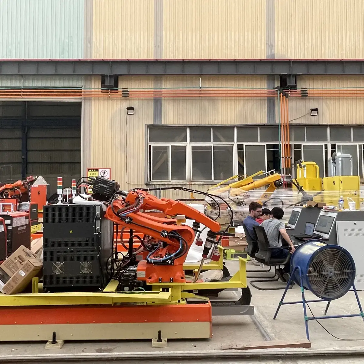 Operators working at a rail-mounted welding robot station.