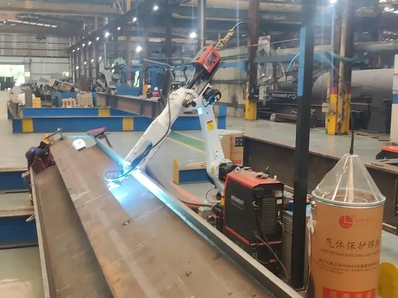 Welding robot on a rail welding along the flange of a long H-beam.
